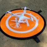 Dron na pomarańczowej macie startowej na piaszczystym podłożu