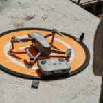 Dron z kontrolerem na macie startowej na zewnątrz w słoneczny dzień