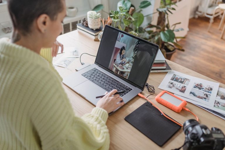 Kobieta edytująca zdjęcia na netbooku przy tablecie graficznym